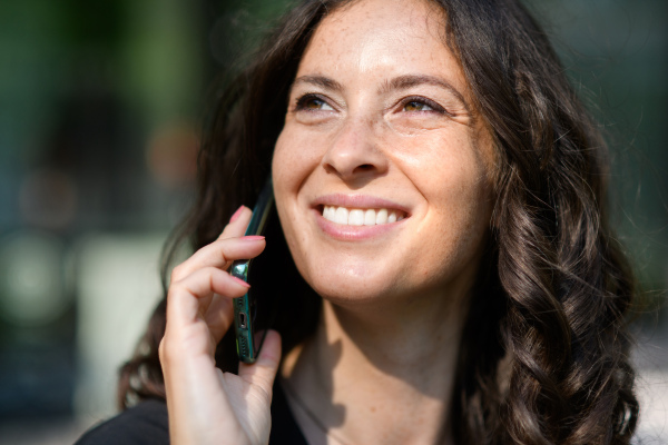 A successful happy businesswoman commuting in the morning in city street, calling on mobile phone.