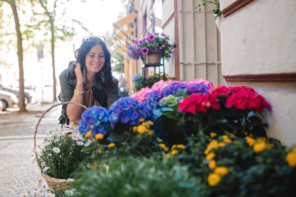 A young urban woman looking at flowers at street shop on sunny day in summer.