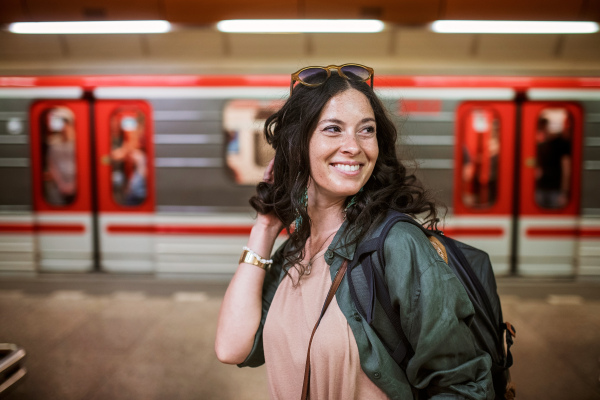 Mid adult woman commuter is standing in a subway station and looking at camera.