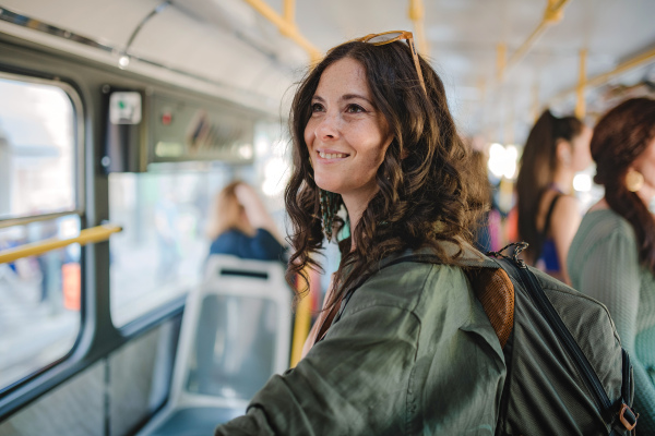 A mid adult woman commuter is standing in bus and travelling in public transport.