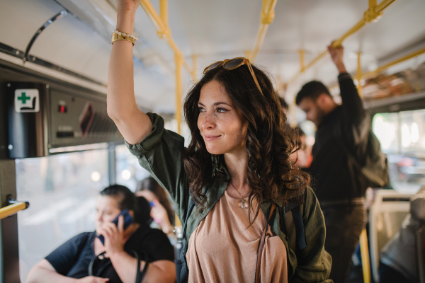 A mid adult woman commuter is standing in bus and travelling in public transport.