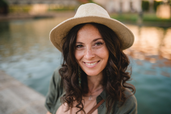 A woman candid portrait from park. Young urban female tourist smiling looking at camera.