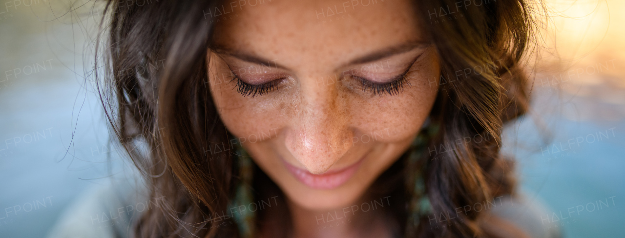 A freckles Woman portrait. Close-up. Beautiful dark haired girl with freckles is looking down on street background