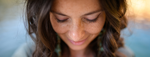 A freckles Woman portrait. Close-up. Beautiful dark haired girl with freckles is looking down on street background