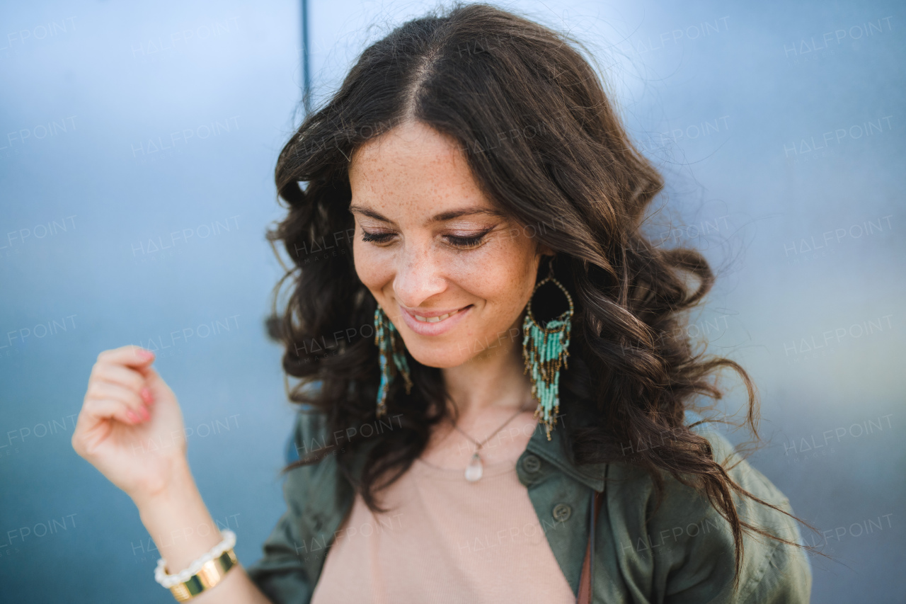 A woman candid portrait from street. Young urban female smiling looking down.