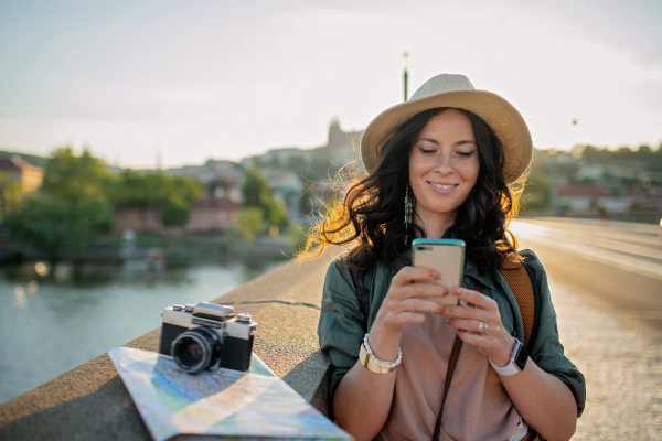 A young beautiful female traveler with backpack and map walking through bridge on sunny day in city. Close up.