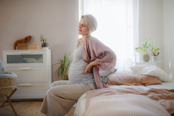 Tired pregnant woman sitting on her bed and resting.