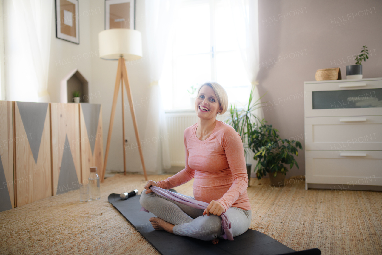 Pregnant woman doing the exercises in her apartment.