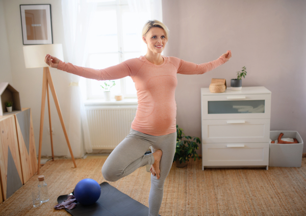 Pregnant woman doing the exercises in her apartment.