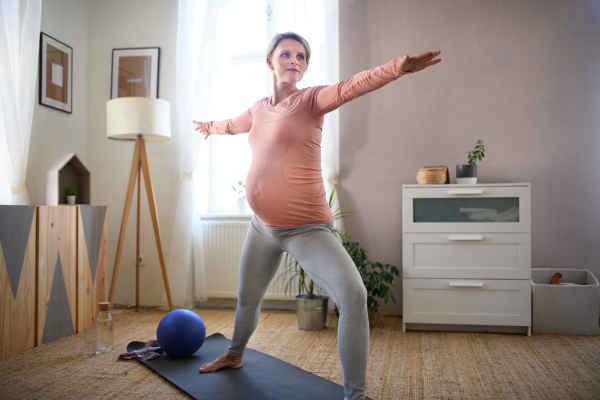 Pregnant woman doing the exercises in her apartment.