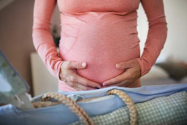 Close-up of a pregnant woman preparing for baby, stroking her belly.