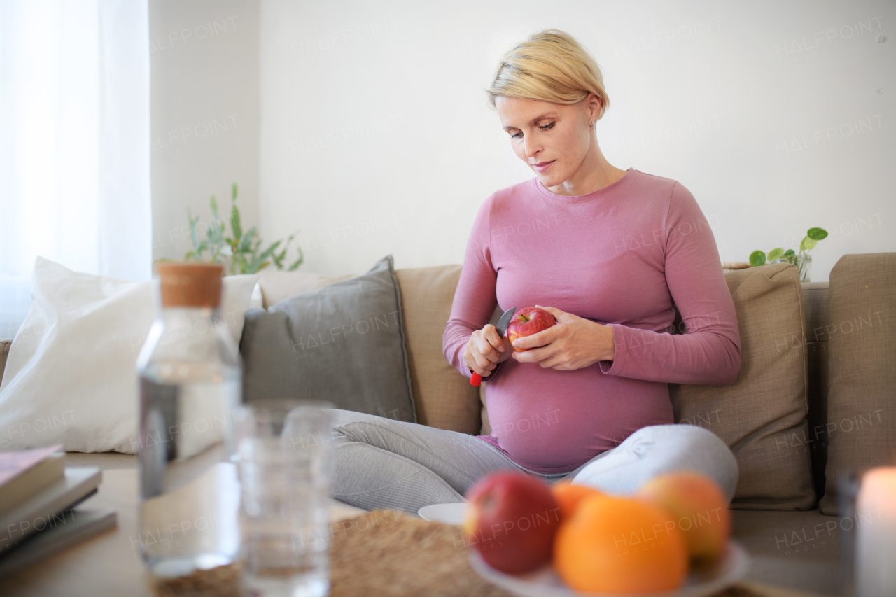 High angle view of pregnant woman cutting an apple.