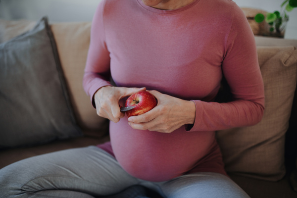 Close up of pregnant woman cutting an apple.