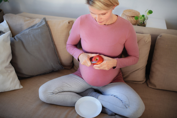 High angle view of pregnant woman cutting an apple.