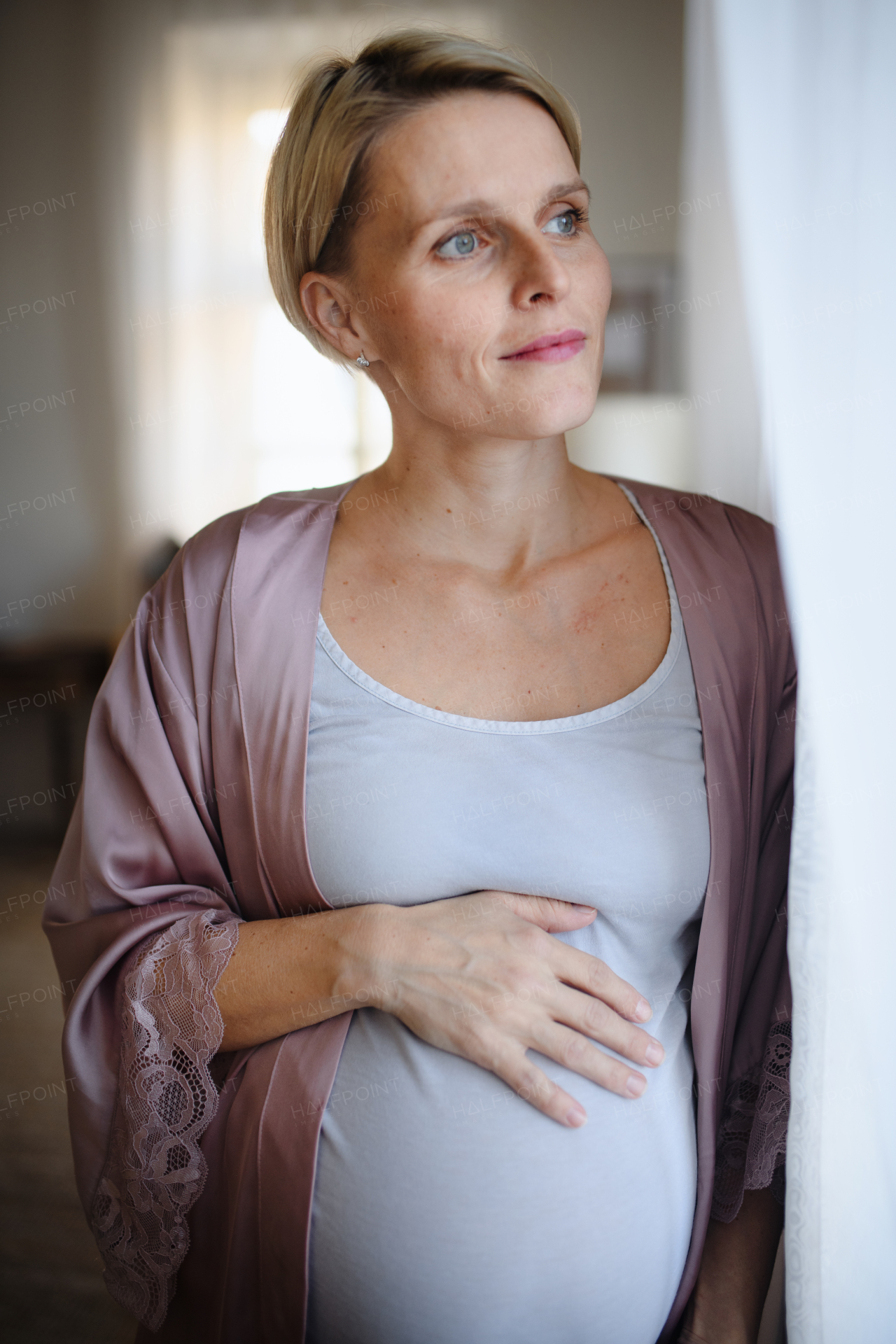 Happy pregnant woman stroking her belly at home.