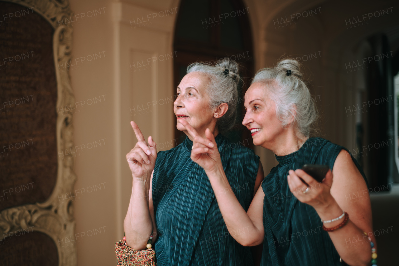 Senior women twins walking in city and admiring the architecture.