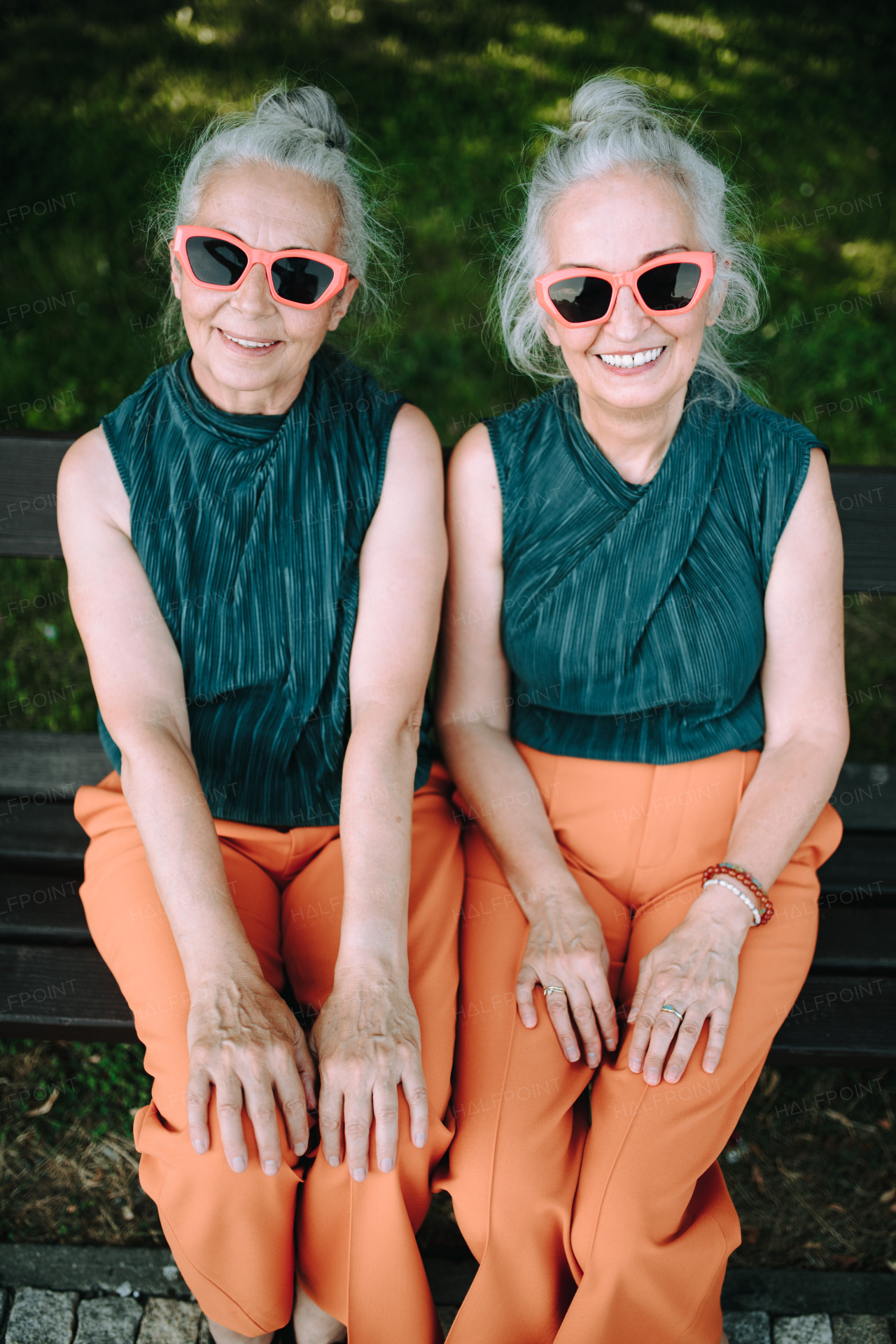 High angle view of happy senior women, twins in same clothes, smiling and posing in a city park.