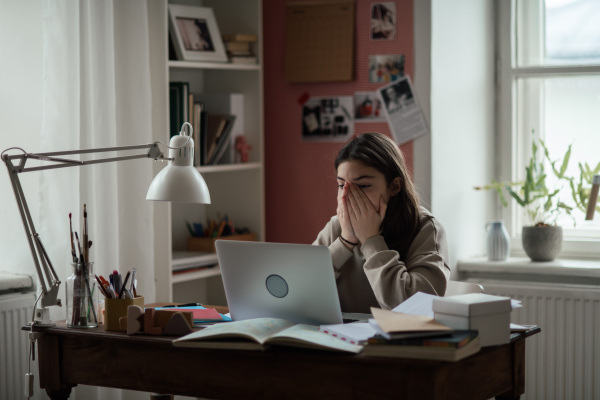 Young teenage girl studying and doing homework in her room.