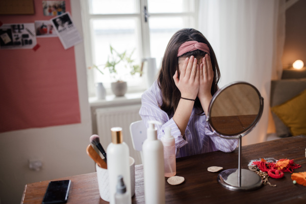 Unhappy girl doing her skin routine in the room.