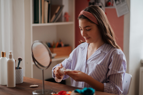 Teenage girl doing her skin care routine in the room.