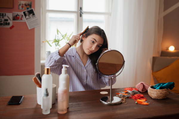 Teenage girl doing her skin care routine and hairstyle in the room.