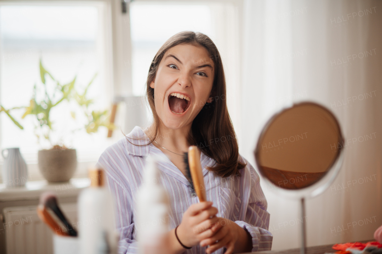 Portrait of excited screaming teenage girl with hair brush in her hand.