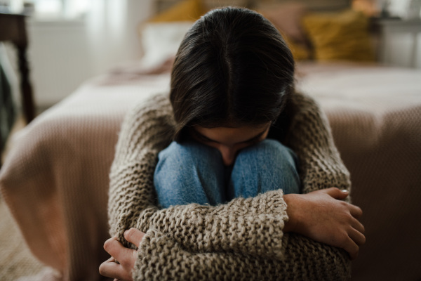 Teenage girl sitting on the floor with head on knees, koncept of mental health.