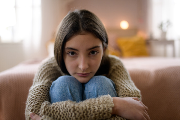 Teenage girl sitting on the floor with head on knees, koncept of mental health.