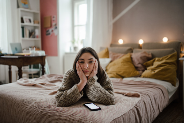 Young teenage girl with smartphone in a room.