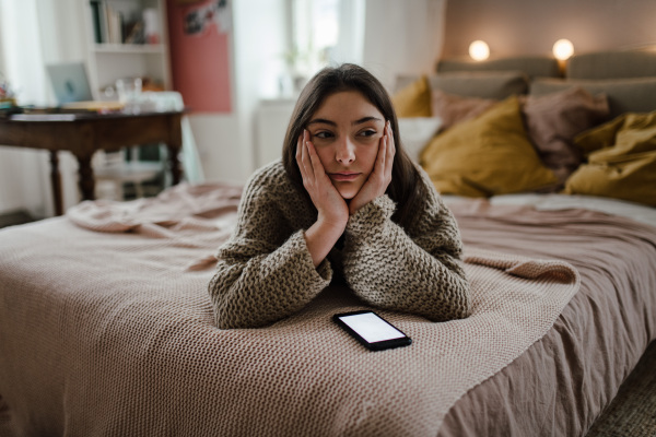 Young teenage girl with smartphone in a room.