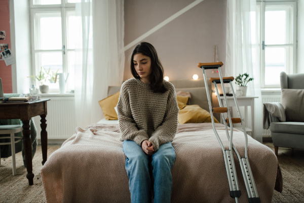 Unhappy girl with broken leg in the room.