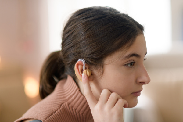 Portrait of teenage girl with hearing aid in the room.