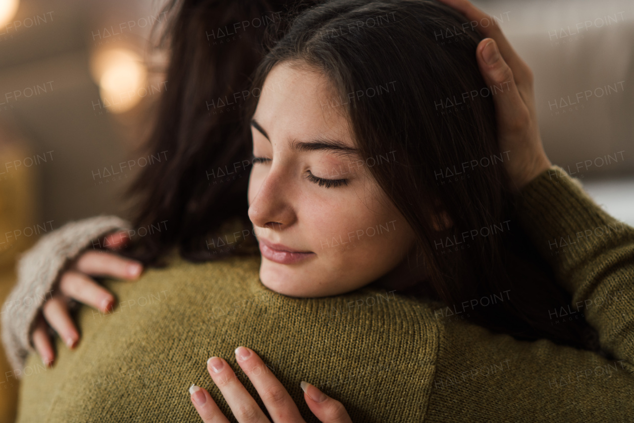 Young teenage girl hugging her mother at home.