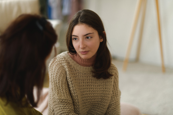 Teenage girl sharing problems with her mother in the room.