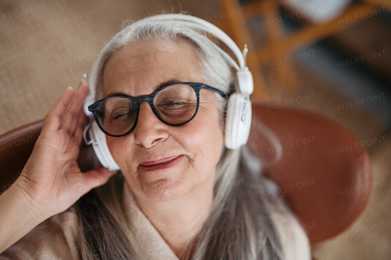 Senior woman resting in a living room, listening music.