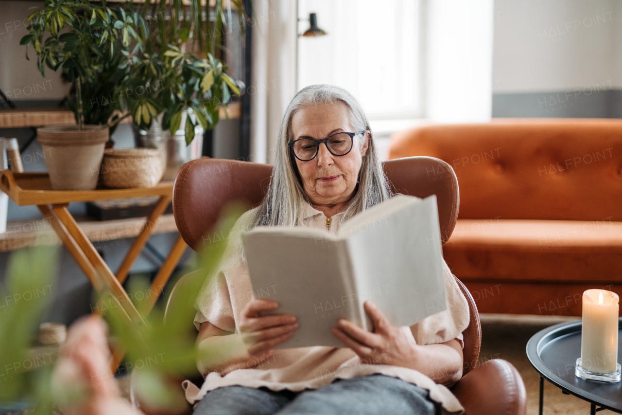 Senior woman reading a book, enjoying time alone in her apartment.