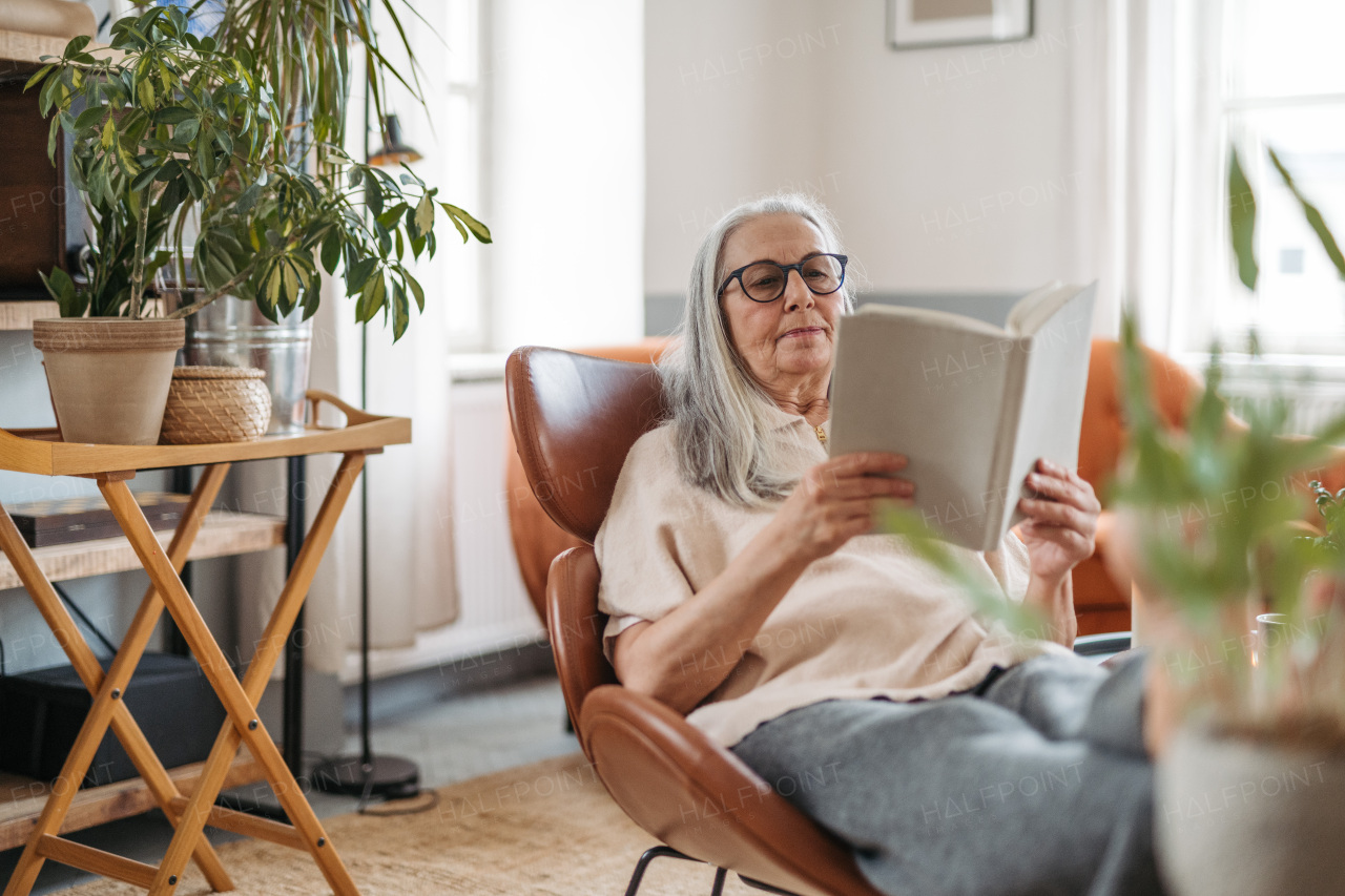 Senior woman reading a book, enjoying time alone in her apartment.