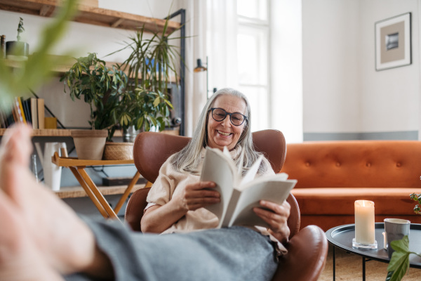 Senior woman reading a book, enjoying time alone in her apartment.