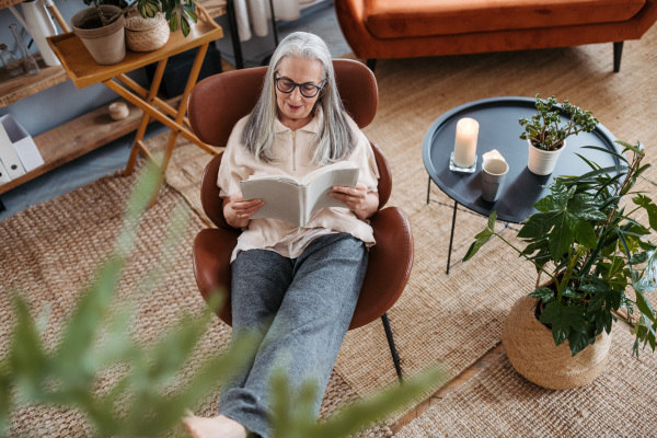 Senior woman reading a book, enjoying time alone in her apartment.