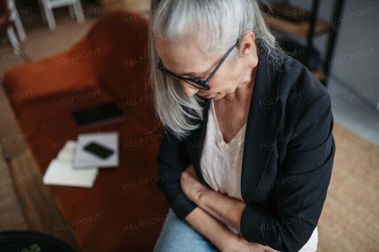 High angle view of a senior woman with stomach ache.