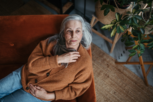 Portrait of pensive senior woman sitting in her home.