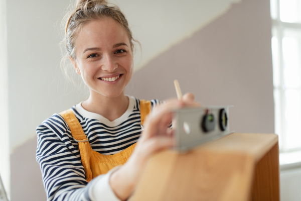 Portrait of young woman remaking shelf in her house. Concept of reusing materials and sustainable lifestyle.