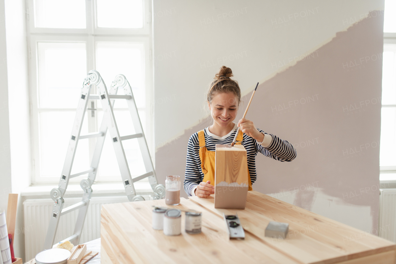 Happy young woman remaking shelf in her house. Concept of reusing materials and sustainable lifestyle.