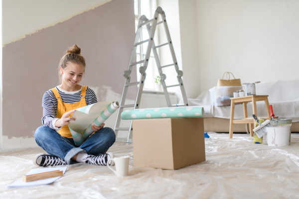 Happy young woman having break during renovation her house. Thinking about new projects. Concept of reusing materials and sustainable lifestyle.