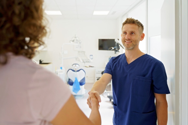 Young dentist shaking hands with a patient.