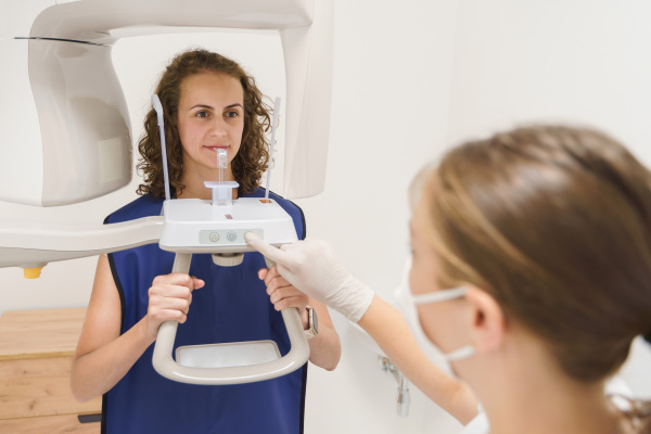 Nurse in a dentist's ambulance doing x-ray scan to young woman patient.