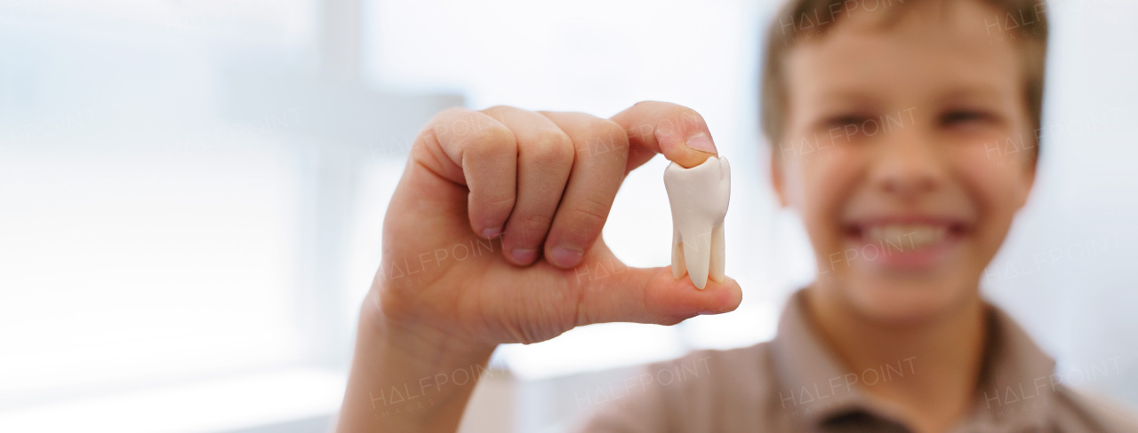 Young boy posing with model of plastic tooth in a dentist ambulance.