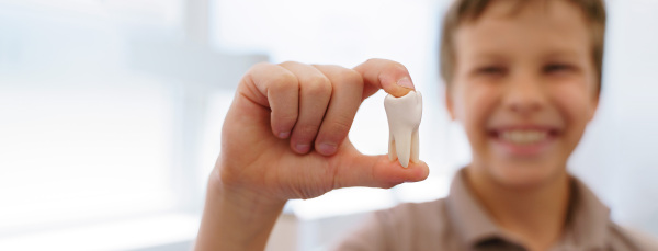 Young boy posing with model of plastic tooth in a dentist ambulance.