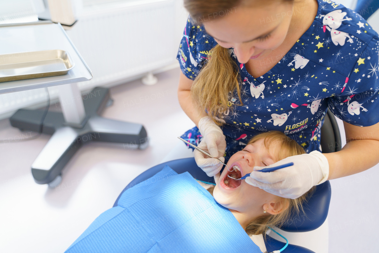 Young woman dentist doing doing preventive examination a little girl.