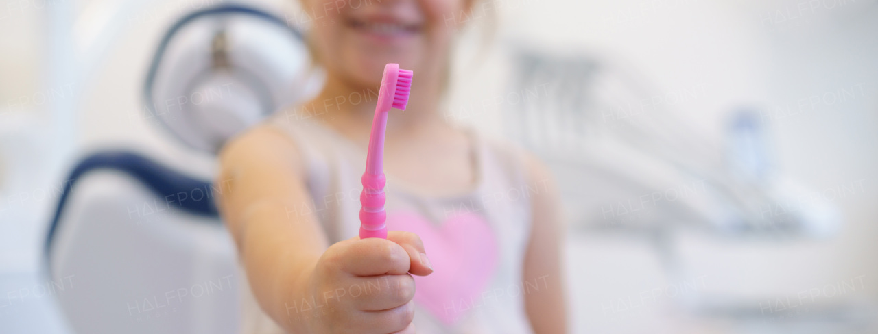 Close-up of little girl holding tootbrush, concept of children oral hygiene, prevention and dental health.